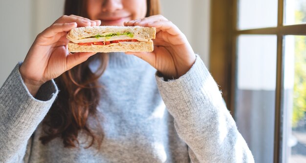 Een mooie vrouw die een stuk volkoren broodje vasthoudt en toont om te eten