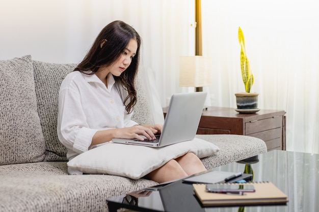 Een mooie vrouw die thuis met een laptop en tabletcomputer werkt.