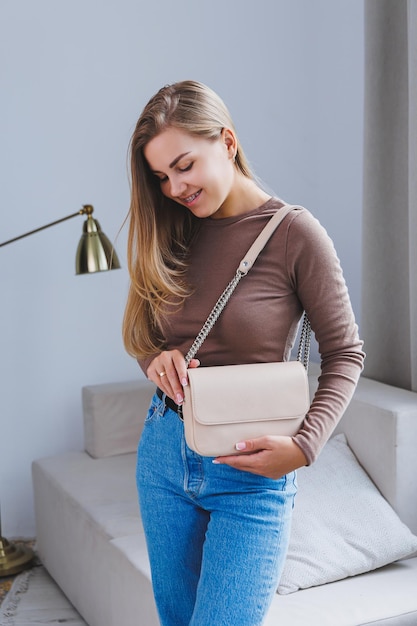 Een mooie vrouw heeft een beige leren tas in haar handen Een kleine cocktailtas voor dames