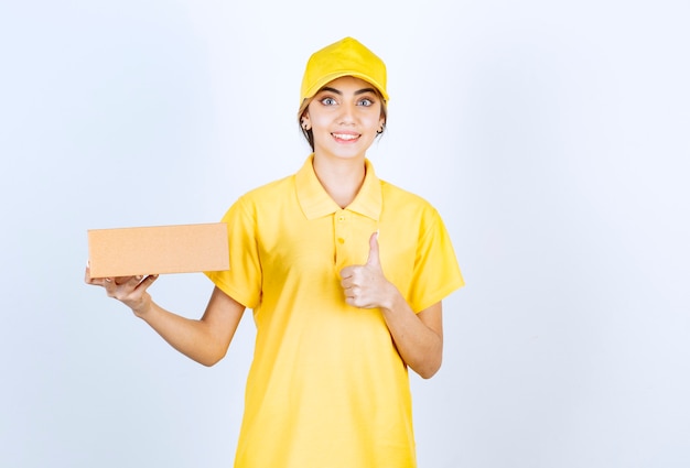 Een mooie vrouw in geel uniform met een bruine lege doos van ambachtelijk papier die een roepnaam maakt.