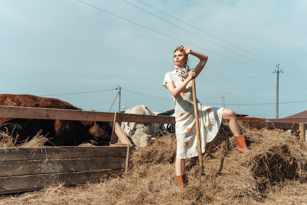 Een mooie vrouw op een boerderij voedt het vee met hooi