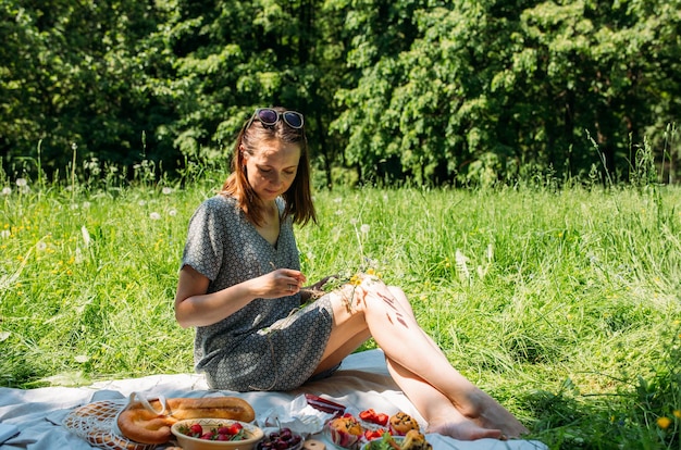 Foto een mooie vrouw op een picknick. ze lacht, eet aardbeien en geniet van de zomer.