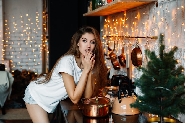 Een mooie vrouw poseert in de keuken, ingericht voor het nieuwe jaar of Kerstmis.