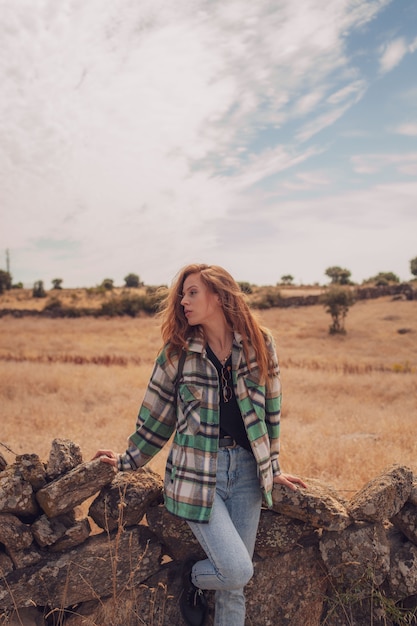 Een mooie vrouw poseert voor de camera met een veld op haar achtergrond