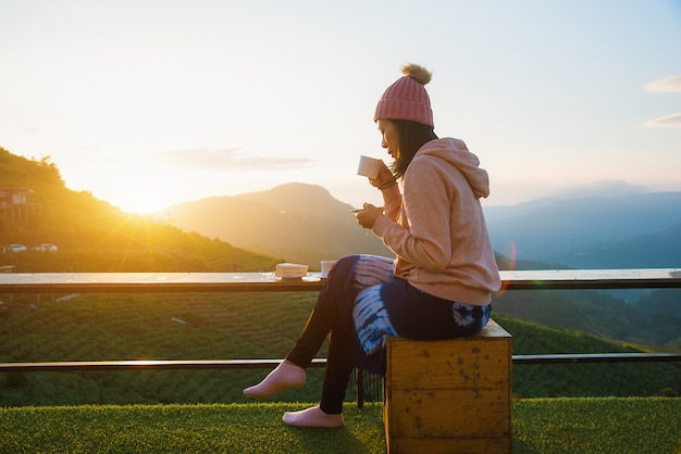 Een mooie vrouw zitten en koffie drinken in de ochtend met een berg