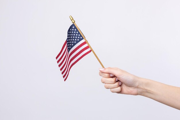 Een mooie vrouwelijke hand houdt een Amerikaanse vlag op een witte achtergrond