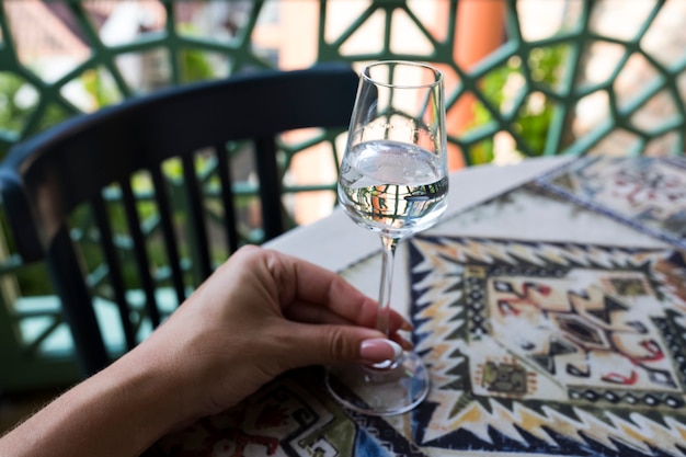 Een mooie vrouwelijke hand houdt een glas vast met grappa, wodka, chacha. Maar de achtergrond van de tafel met het nationale tafelkleed. Hoge kwaliteit foto