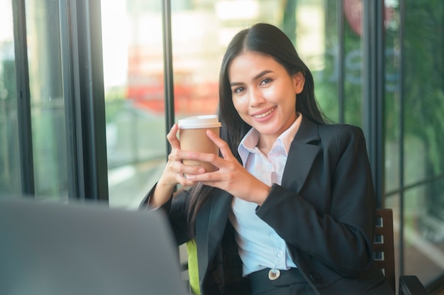 Een mooie zakenvrouw analyseert financiële gegevens via de computer, koffie drinken in de coffeeshop