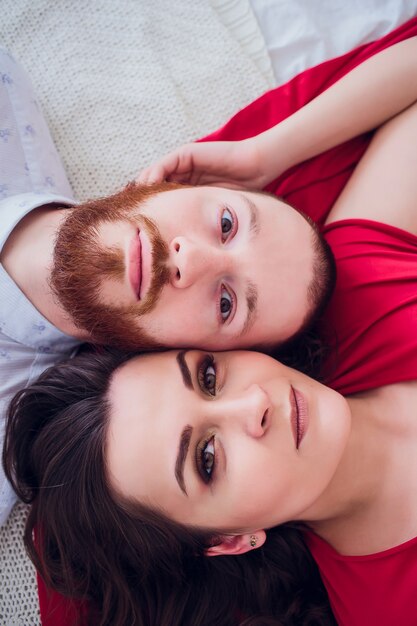 Een mooie zwangere vrouw in zwart ondergoed ligt op een grijze sluier. Het bed is versierd met verse bloemen. Het meisje heeft blond haar, ze glimlacht. Uitzicht van boven.