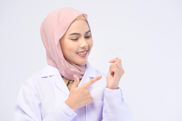 Een moslim vrouwelijke tandarts met invisalign beugels op een witte achtergrond studio