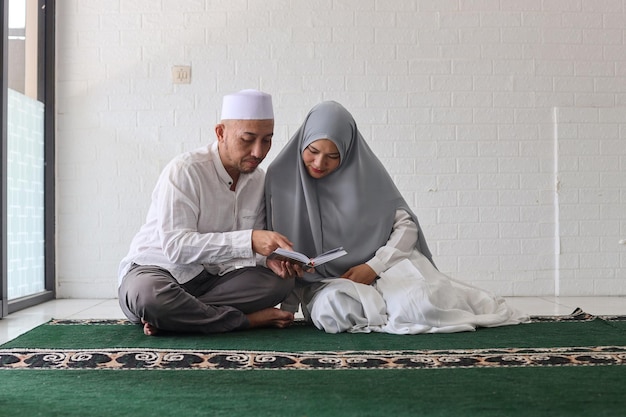 Een moslimpaar dat samen de koran leest, leert zijn vrouw de koran reciteren tijdens het ramadanfeest