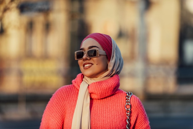 Een moslimvrouw met een hijab loopt door de straten van de stad in een moderne outfit gecombineerd met een zonnebril selectieve focus