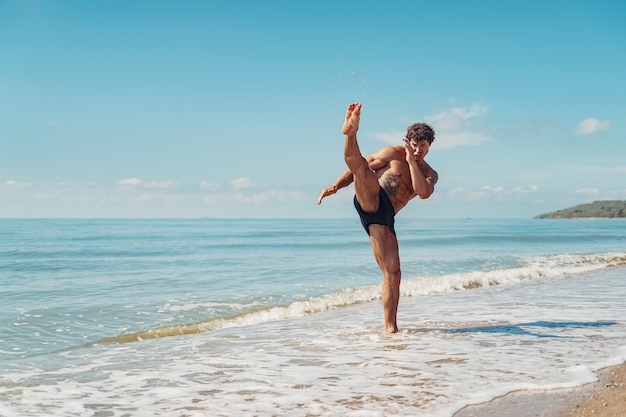 Een muay thai of kickbokser training met schaduwboksen buiten aan de kust