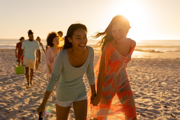 Een multi-etnische groep vrienden die genieten van hun tijd samen op een strand op een zonnige dag, blootsvoets lopend en met elkaar pratend