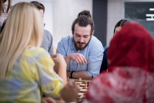 Foto een multi-etnische groep zakenmensen die aan het schaken zijn tijdens een pauze in een modern startup-kantoor