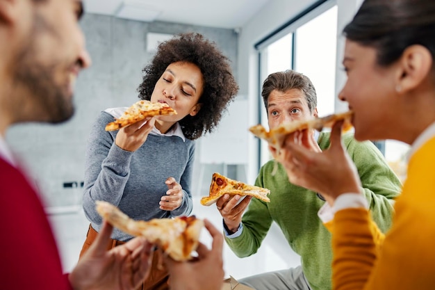 Een multiculturele zakenlui die pizza eten voor de lunch op kantoor voor een lunchpauze