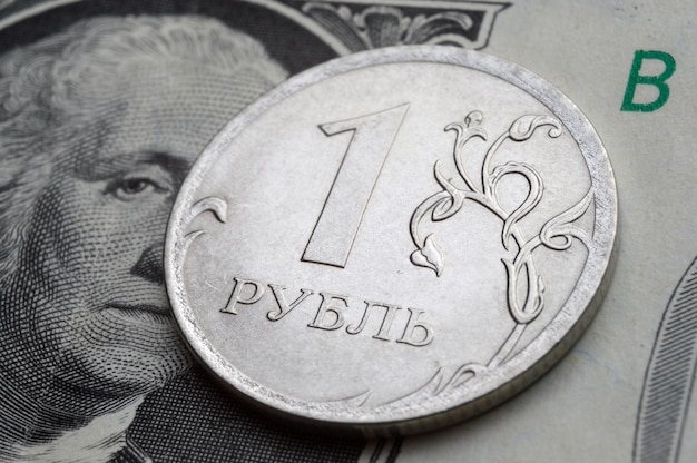 Een munt met een nominale waarde van 1 roebel ligt op een bankbiljet van de Amerikaanse dollarclose-up