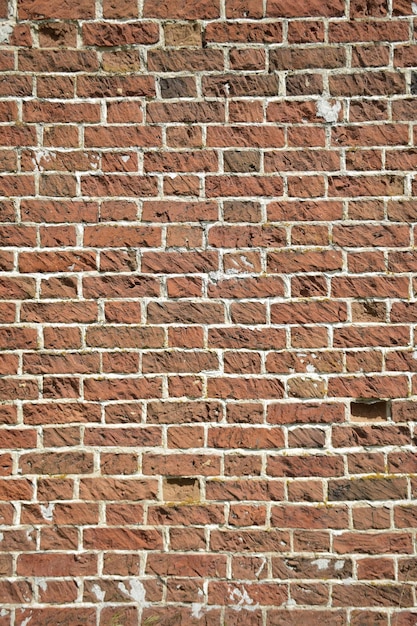 Een muur van oude gebarsten bakstenen met een verweerd en vervaagd oppervlak Gerestaureerd metselwerk van een oud huis