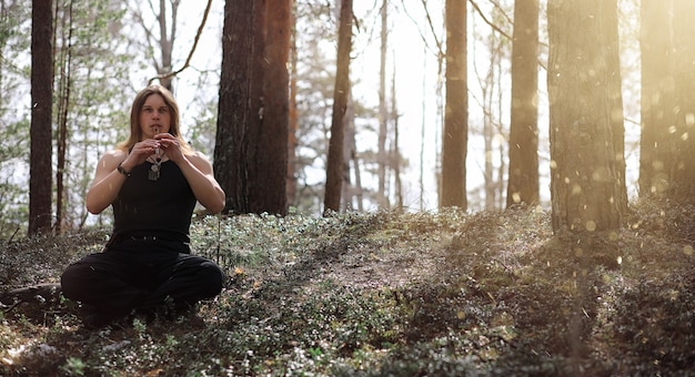 Een muzikant met een hulpmiddel in de natuur. De mens speelt een fluit in een dennenbos. De muziek van de druïden in het lentebos.