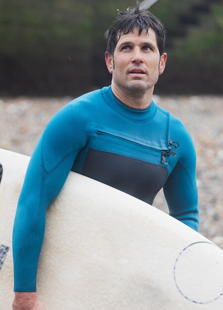 Foto een nadenkende surfer houdt een plank vast bij de kopieerruimte aan de kust.