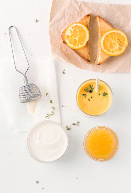 Een natuurlijk ontbijt met sandwiches met sinaasappeljam en Lassi. In de buurt zijn yoghurtingrediënten.