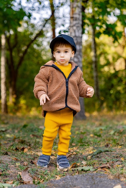 Een nieuwsgierige kleine jongen die de natuur verkent in een bruin jasje en een gele broek Een kleine jongen in een bruine jasje en een gele broek