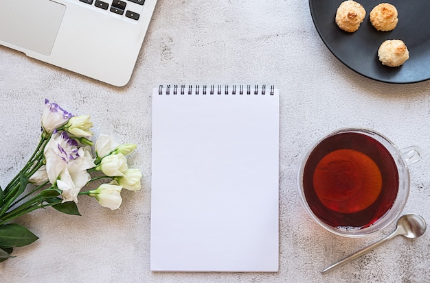 Een notitieblok voor de dagelijkse planning met ontbijtinstelling, laptop en bloemen