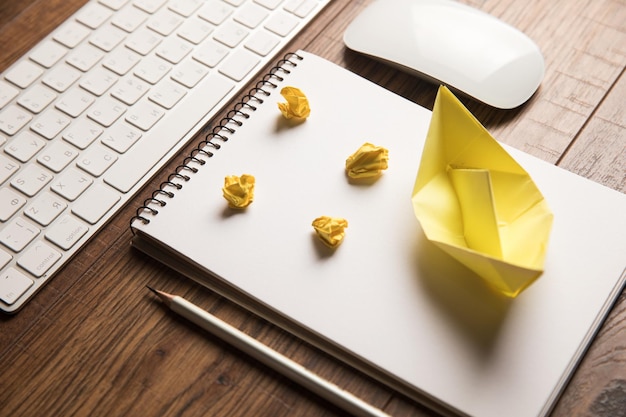 Een notitieboekje met een gele papieren boot erop en een muis aan de zijkant.