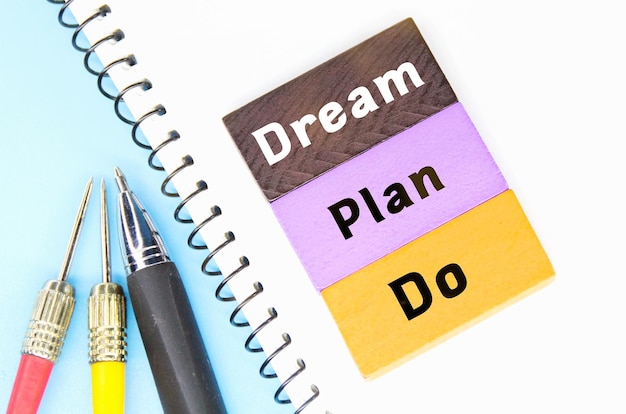 Foto een notitieboekje met een notitieblok waarop droom en plan staat.