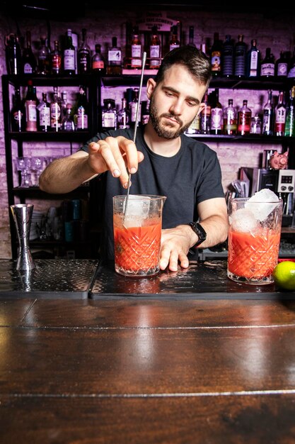 Een ober roert een glas cocktail boven een toog