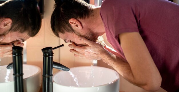 Een ochtendroutine, jonge, bebaarde mannelijke persoon die het gezicht afwast