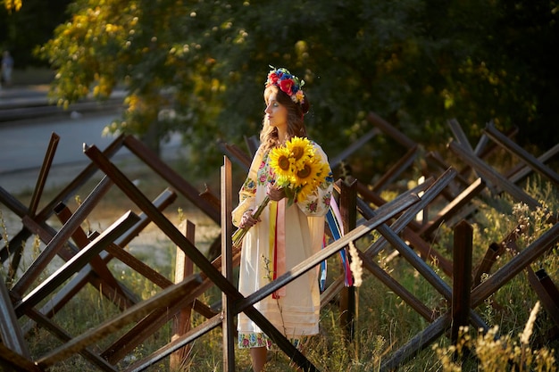 Een Oekraïens meisje in een Oekraïense nationale vyshyvanka-jurk met een boeket zonnebloemen, anti-tank hij