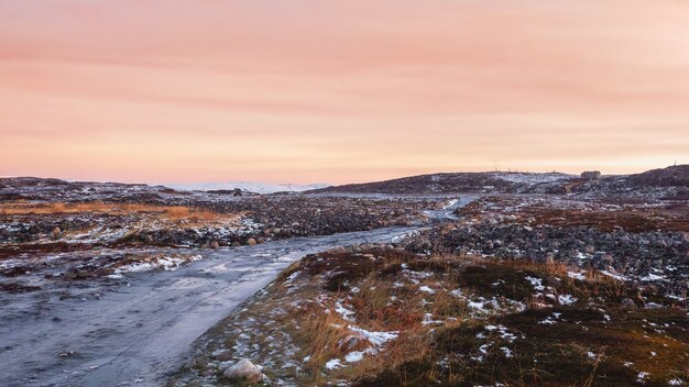 Een onbegaanbare ijzige weg door de wintertoendra. een ruwe, rotsachtige weg die zich in de verte uitstrekt. kola-schiereiland.