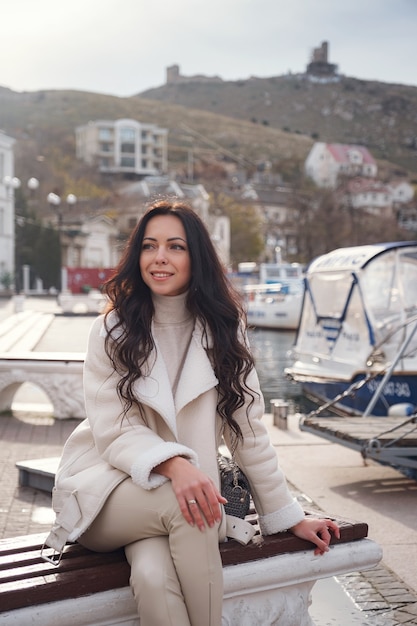 Een onbezorgde blanke vrouw in beige kleding die op een warme, winderige dag geniet van het uitzicht op zee