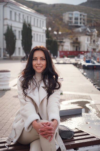 Een onbezorgde blanke vrouw in beige kleding die op een warme, winderige dag geniet van het uitzicht op zee