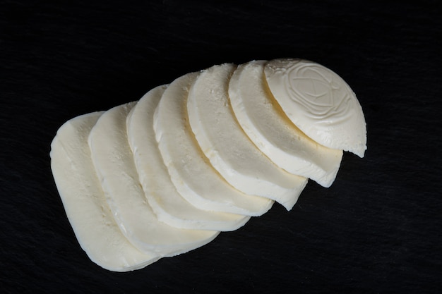 Een onderstel van mozzarella kaas op een zwarte achtergrond