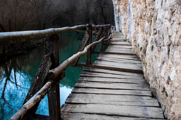 Een ongelijke houten loopbrug leidt naar een rivier met blauw water
