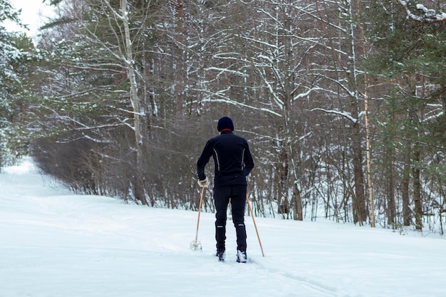 Een onherkenbare man loopt langlaufen in een winters natuurpark Buitenactiviteiten