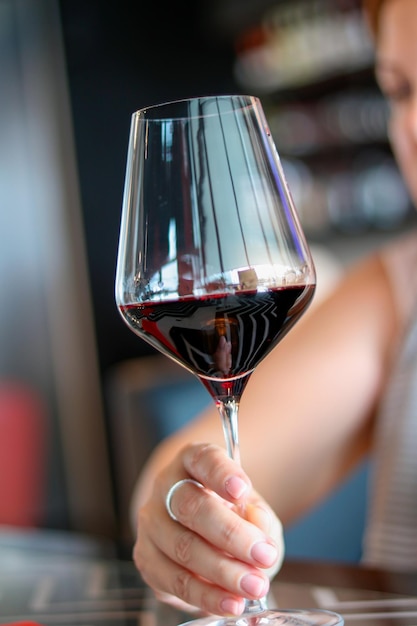 Een onherkenbare vrouw houdt een glas rode wijn in haar hand Close-up Schoonheid en elegantie van vrouwen