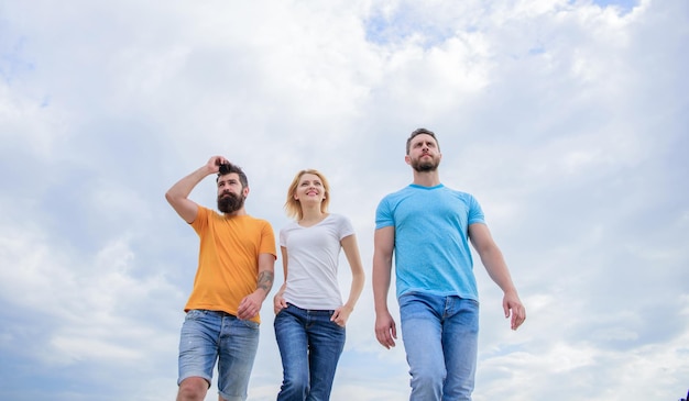 Een ontspannen stijl groep mensen in vrijetijdskleding jonge mensen in casual stijl op bewolkte hemel modemensen zien er casual uit in zomeroutfit mooie vrouw en mannen vrienden die buiten lopen