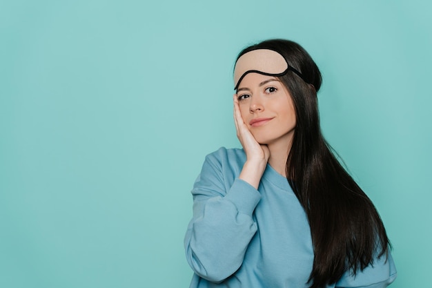 Een ontspannen, vrolijke brunette vrouw raakt haar gezicht aan na het ontwaken, verheugt zich over een goede dag en slaapt