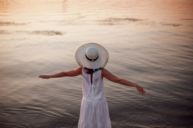 Een ontspannen vrouw geniet van de zon vrijheid en het leven op een prachtig strand bij zonsondergang het concept van vacati...