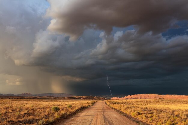 Foto een onverharde weg die leidt naar donkere onheilspellende stormwolken en bliksem in zuid-utah