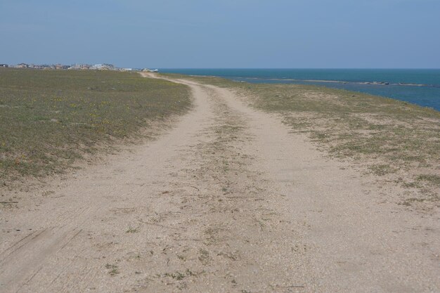Een onverharde weg leidt naar het strand en de oceaan.