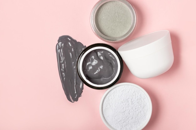 Een open cosmetische pot, tegen de achtergrond van een besmeurde crème of cosmetisch gezichtsmasker. Zuiverend en hydraterend kleimasker. Bovenaanzicht, plat gelegd