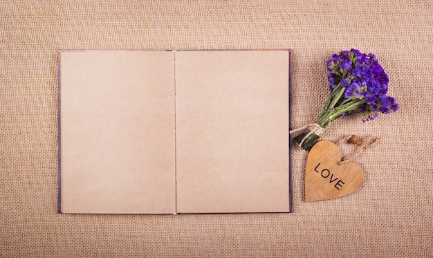 Een open dagboek met lege pagina's, een boeket droge wilde bloemen en een hart van hout.