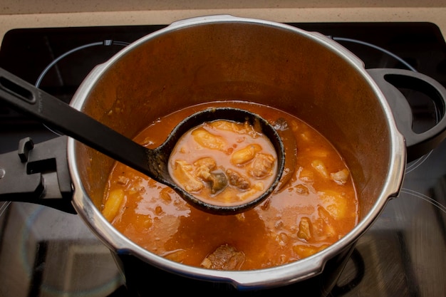 Een open snelkookpan met een bonenstoofpot van bovenaf gezien Typische Asturische Fabada-stoofpot