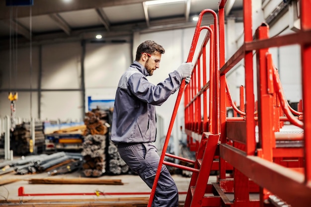 Een operator klimt op de machine om deze in de staalfabriek te controleren