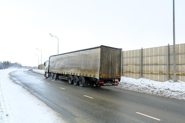 Een oplegger, oplegger, oplegger en oplegger om vracht te vervoeren. Vrachtvervoer in barre winteromstandigheden op gladde, ijzige en besneeuwde wegen