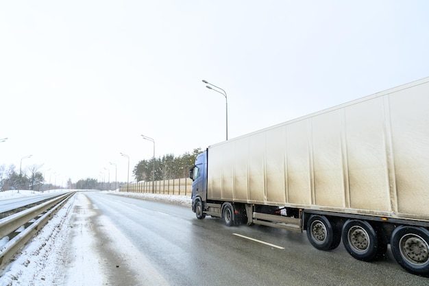 Een oplegger vrachtwagen oplegger trekker eenheid en oplegger om vracht vrachtvervoer te vervoeren in harde winteromstandigheden op glibberige ijzige en besneeuwde wegen